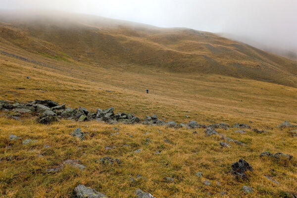 A distant, nearly invisible in the landscape Prof crosses the Col du Serre Chevalier 