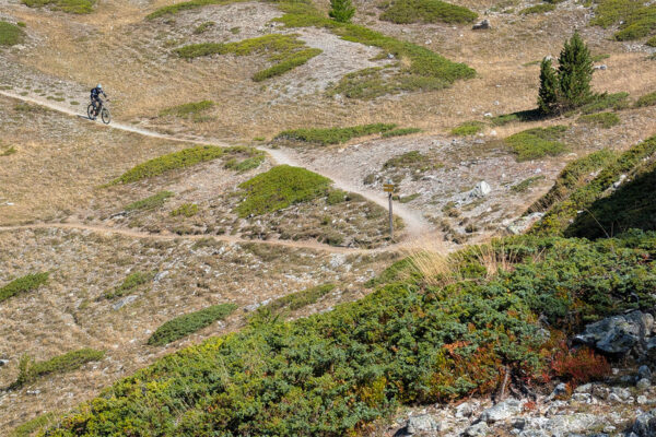 A mountain biker in the distance picks his way across a barren landscape near Col du Tronchet
